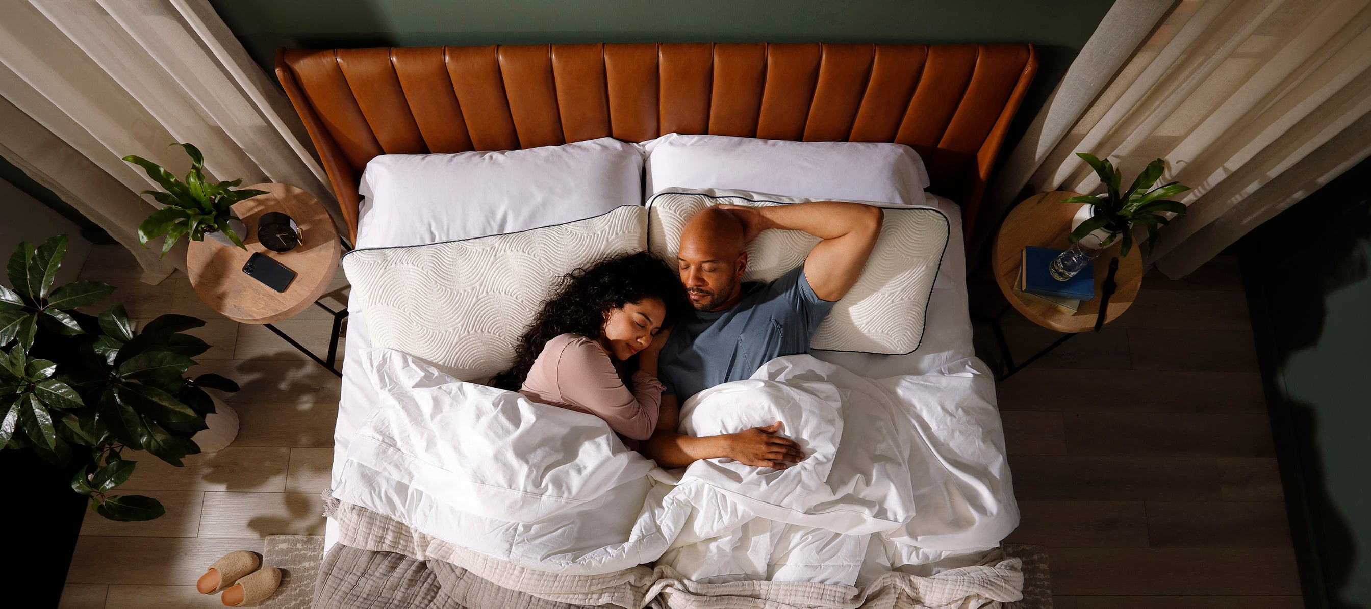 Diverse couple sleeping in bed on comfortable pillows in stylish bedroom