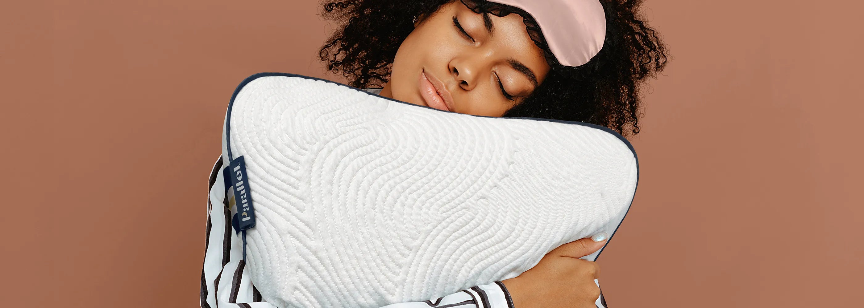 Woman wearing sleep mask hugging Parallel Pillow